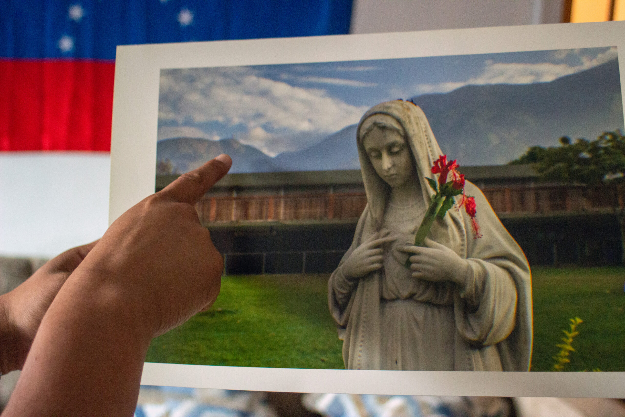 A finger pointing at a photograph of a mountain and the Virgin Mary.